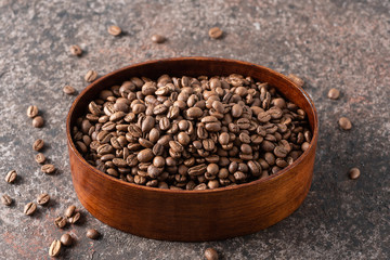 Roasted coffee beans in a wooden box on a dark background.