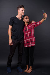 Portrait of happy young multi ethnic couple taking selfie together