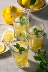Glasses of homemade lemonade with ice and fresh mint on sunny table. Concept for healthy detox drink.