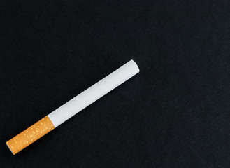 One cigarette on a black background close-up.