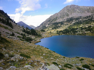 Fototapeta na wymiar High mountain lake on a sunny day with the mountains behind. Horizontal image