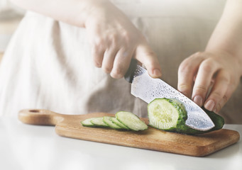 Chef slicing vegetables and cucumber on the table in restaurant. Process of cutting and preparation food in kitchen.