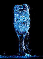 Splashes and drops of water in a glass are isolated on a black background.