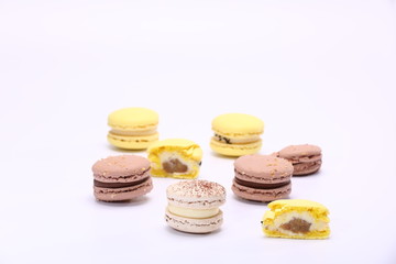 Colorful whole macaroons and piece with stuffing macarons isolated on white background. Delicious French sweet cookie.