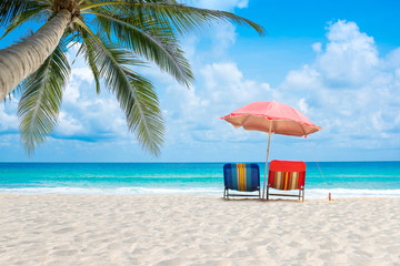 Beach chairs with umbrella and sand beach in summer beach and tropical sea.