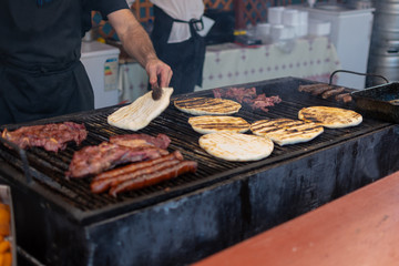 Chef preparing meat on the grill, during outdoor outside food festival
