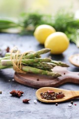 
Fresh herbs, asparagus, lemons, spices on the kitchen table for preparing healthy homemade food from organic products