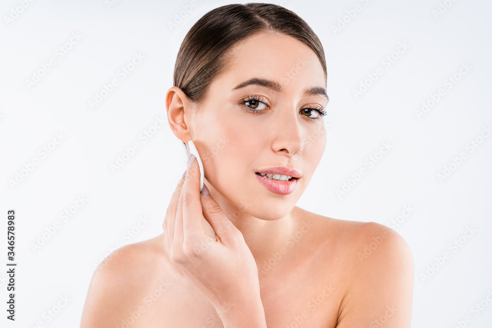 Wall mural Beautiful young woman with clean skin posing naked holding cotton pad isolated over white wall background