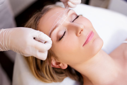 close up of young woman undergoing eyebrow correction procedure in beauty salon