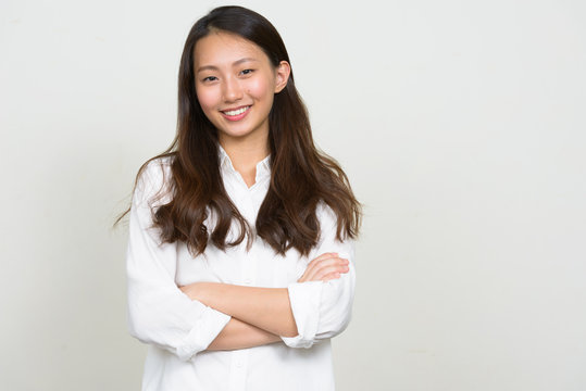 Portrait of happy young beautiful Asian businesswoman smiling with arms crossed