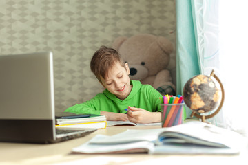 Fototapeta na wymiar Child boy doing homework writing and reading at home. Distance learning child on a table. Concept online education