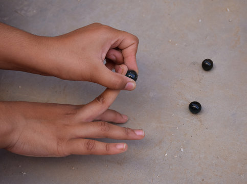 Indian Childhood games - Child playing with glass marbles which is an old Indian village game. Glass Marbles are also called as Kancha in Hindi Language.