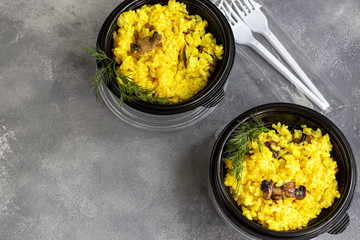 Italian risotto with champignons and parmesan. Food is delivered to your home in quarantine in disposable utensils. Rice is seasoned with turmeric and herbs. Copy space