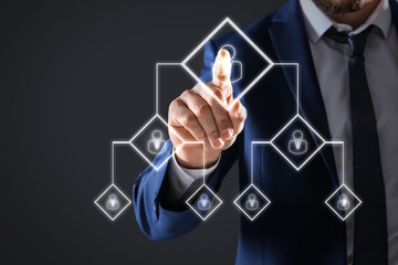 Man touching icon on virtual screen with structure of organization, closeup. Business corporation