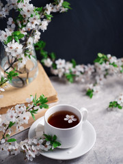 A Cup of tea, blooming branches of white cherries and books. Springtime