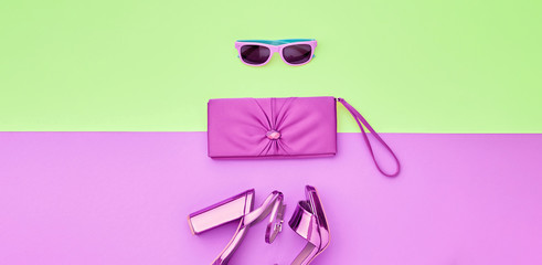 Fashion accessories minimal flat lay. Shoes heels, trendy handbag clutch. Pop art concept. Woman fashionable accessories on purple green, top view, banner. Creative design color