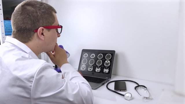 A radiologist doctor examines the result of a computed tomography of the brain on a computer monitor. Diagnosis of neurological and oncological diseases