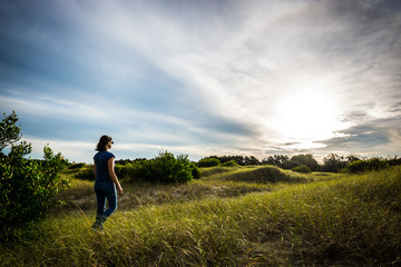 Joven mujer caminando en el pasto al atardecer © Germán Zeiler