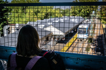 Joven mujer viendo el tren a través de unas rejas