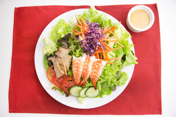 vegetable salad top with shrimps and grilled sliced mushroom in white plate  served with thousand island dressing 