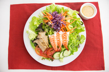 vegetable salad top with shrimps and grilled sliced oringi mushroom in white plate  served with thousand island dressing 