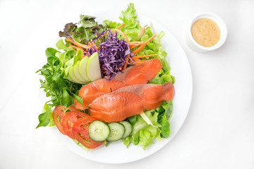 vegetable salad top with smoked salmon and sliced green apple on a white plate isolated white background