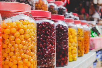 Pickled Fruits in glass jar arranging in the shop shelf.