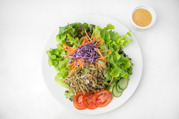 vegetable salad top with fried minnow fish in white plate  served with thousand island dressing in a dipping bowl