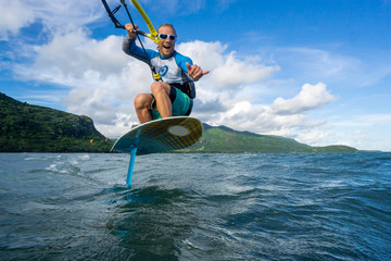 professional kiter t rides by hydrofoil on a beautiful background of mountain, spray and beautiful...