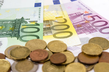 100, 200 and 500 euro banknotes and coins on white. Close-up.