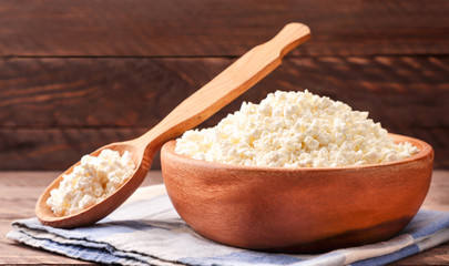 Cottage cheese in a plate and spoon with a napkin on a wooden background. Food photo