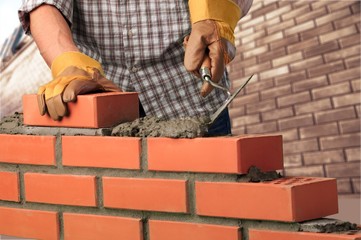 Man worker installing brick masonry wall with a trowel