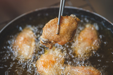 Frying salt chicken wing with cooking oil.
