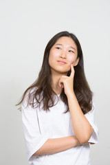 Portrait of young beautiful Asian woman thinking