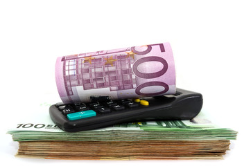 500 euros rolled up on a calculator and euro banknotes. White background. Close-up.