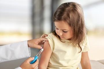 Doctor vaccinating little girl on hospital background