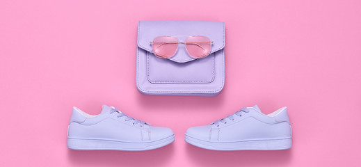 Fashion accessories minimal flat lay. Trendy shoes sneakers, handbag clutch. Pop art purple concept. Woman fashionable accessories on pink, top view, banner. Creative design color