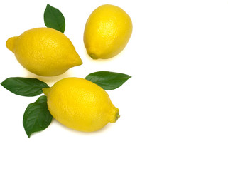 Three whole yellow lemons with green leaves isolated on white background