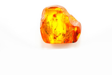 A transparent yellow piece of amber with insects inside on a white background. Sun stone made from fossilized hardened resin trees. Natural mineral for jewelry. Inclusions in pitch. Crystal