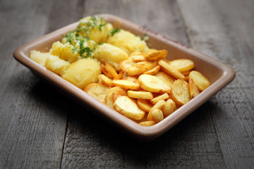 Baked potato slices and boiled potatoes. Addition to dishes.
Appetizing homely dish on a wooden table.