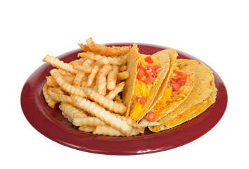 Three crispy tacos on a red plate with french fries, isolated on white. Popular Americanized Mexican food.