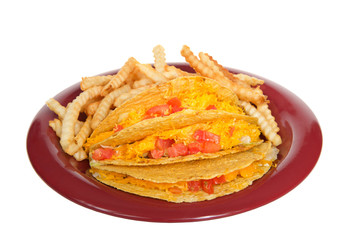 Three crispy tacos on a red plate with french fries, isolated on white. Popular Americanized Mexican food.