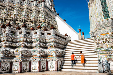 A man and woman walk up the stairs at the Prang of Arun Temple, Bangkok, Thailand.