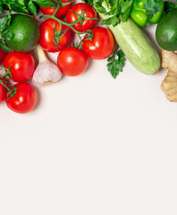 Fresh green and red vegetables on a light background, top view, free space for text. Tomatoes, peppers, avocados, zucchini and parsley flat lay, copy space. Healthy vegetarian food concept.