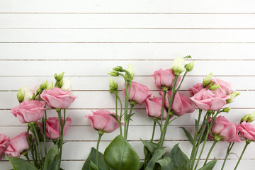 Pink eustoma flowers on wooden background in vintage style. Romantic wedding background. Top view.