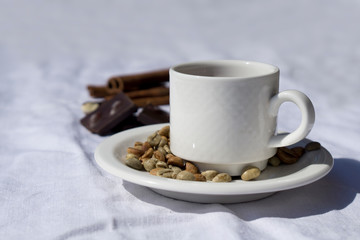 Coffee composition  with  white cup    of coffe  and beans of coffe, cinnamon, Chocolate,  on  linen tableclothtable