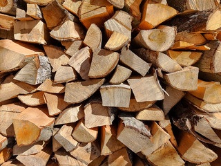Background of dry chopped firewood logs stacked up on top of each other in a pile.Row of fire wood stock for winter.Selective focus. firewood logs