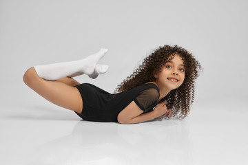 Little female gymnast demonstrating boat exercise.