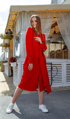 Portrait of a beautiful young elegant sexy blonde woman in the cafe. Young beauty poses near woodan cafe. Red dress.