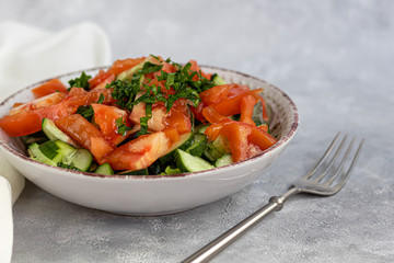 Diet salad made from fresh vegetables. Cucumbers, tomatoes, green onions and chili peppers. Parsley greens. Dressed with olive oil.